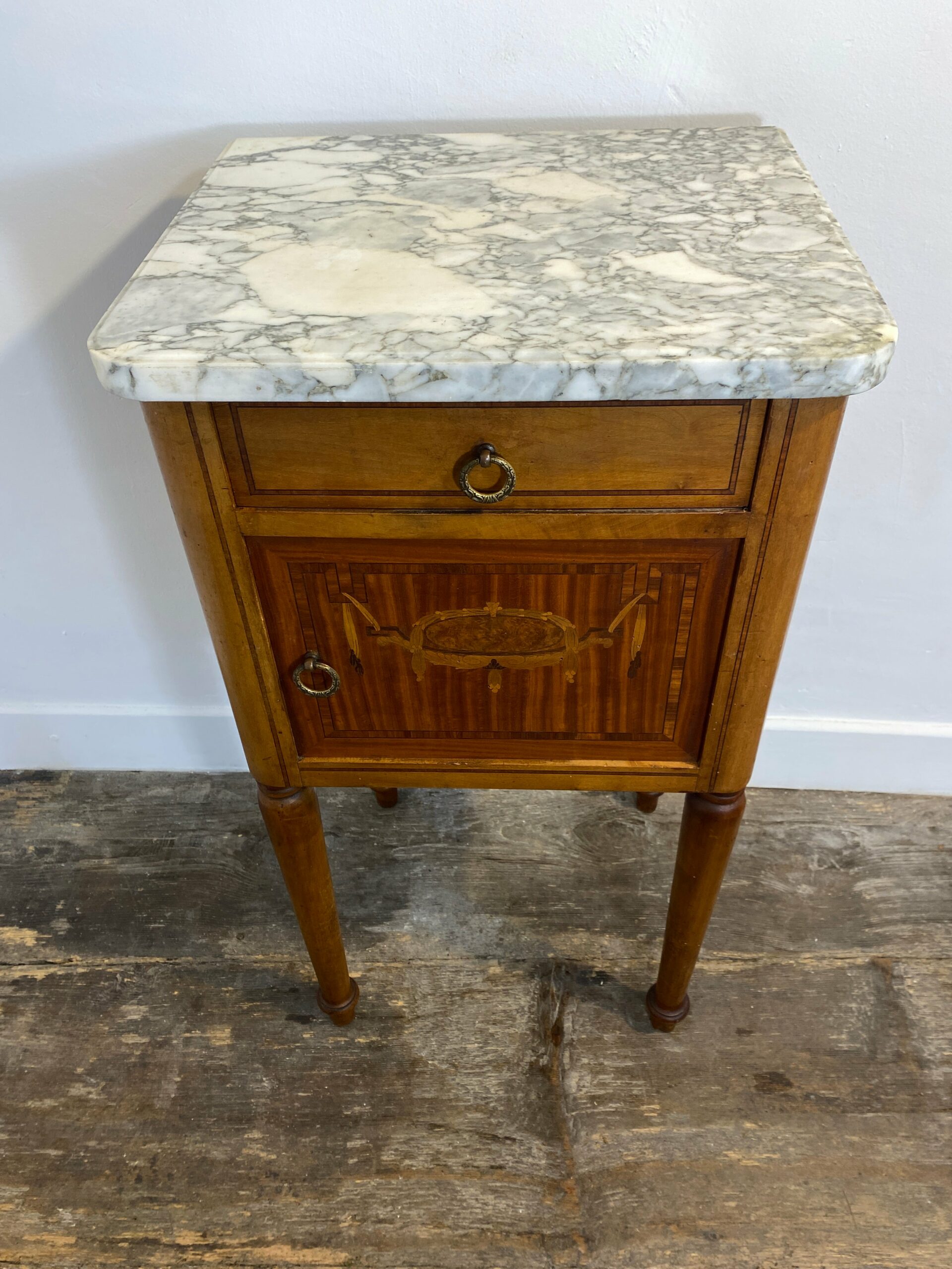 Antique Louis XVI-style nightstand with white marble top and intricate marquetry inlay, late 19th century French bedside cabinet with brass ring pulls