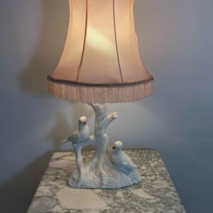 Vintage French ceramic table lamp with two white birds on tree trunk base, pink satin shade with fringe trim, Victorian Revival style 1950s