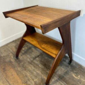Vintage 1950s mid-century modern side table with rolling casters and sculptural Z-form solid wood legs in warm hardwood tones atomic era design